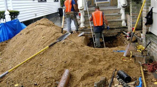 Contractors performing foundation protection and exterior drainage excavation near residential home steps in Boulder, CO