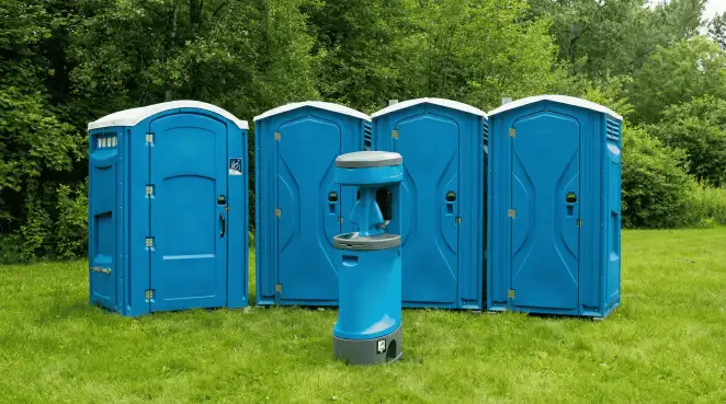 Four blue portable toilets and a matching hand washing station on grass near trees, a common sight at local outdoor events in Boulder, CO